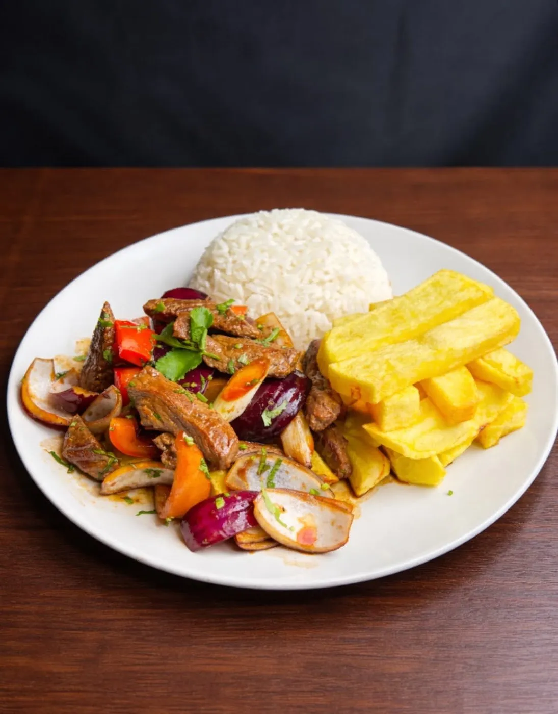 Lomo saltado con arroz blanco y patatas fritas en un plato blanco