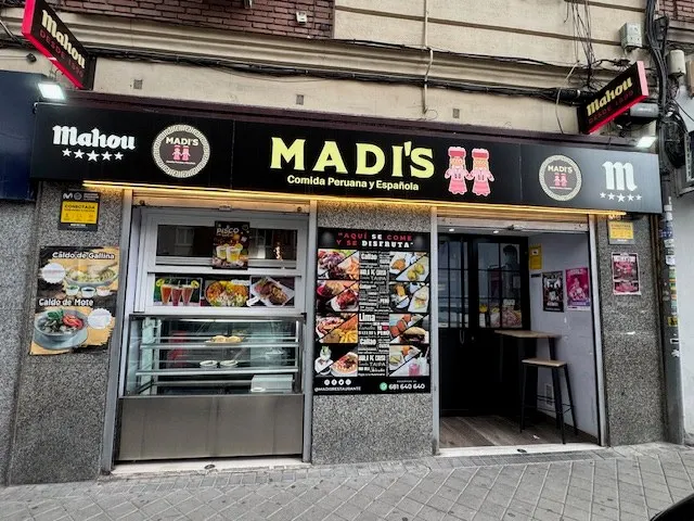Fachada del restaurante con el rótulo Madi's, Comida Peruana y Española, y la vitrina de la entrada